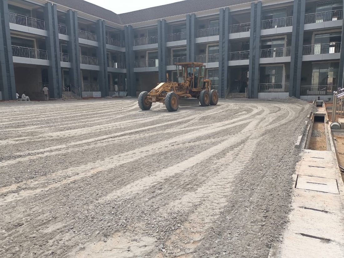 Motor grader levelling the courtyard of an institutional building development