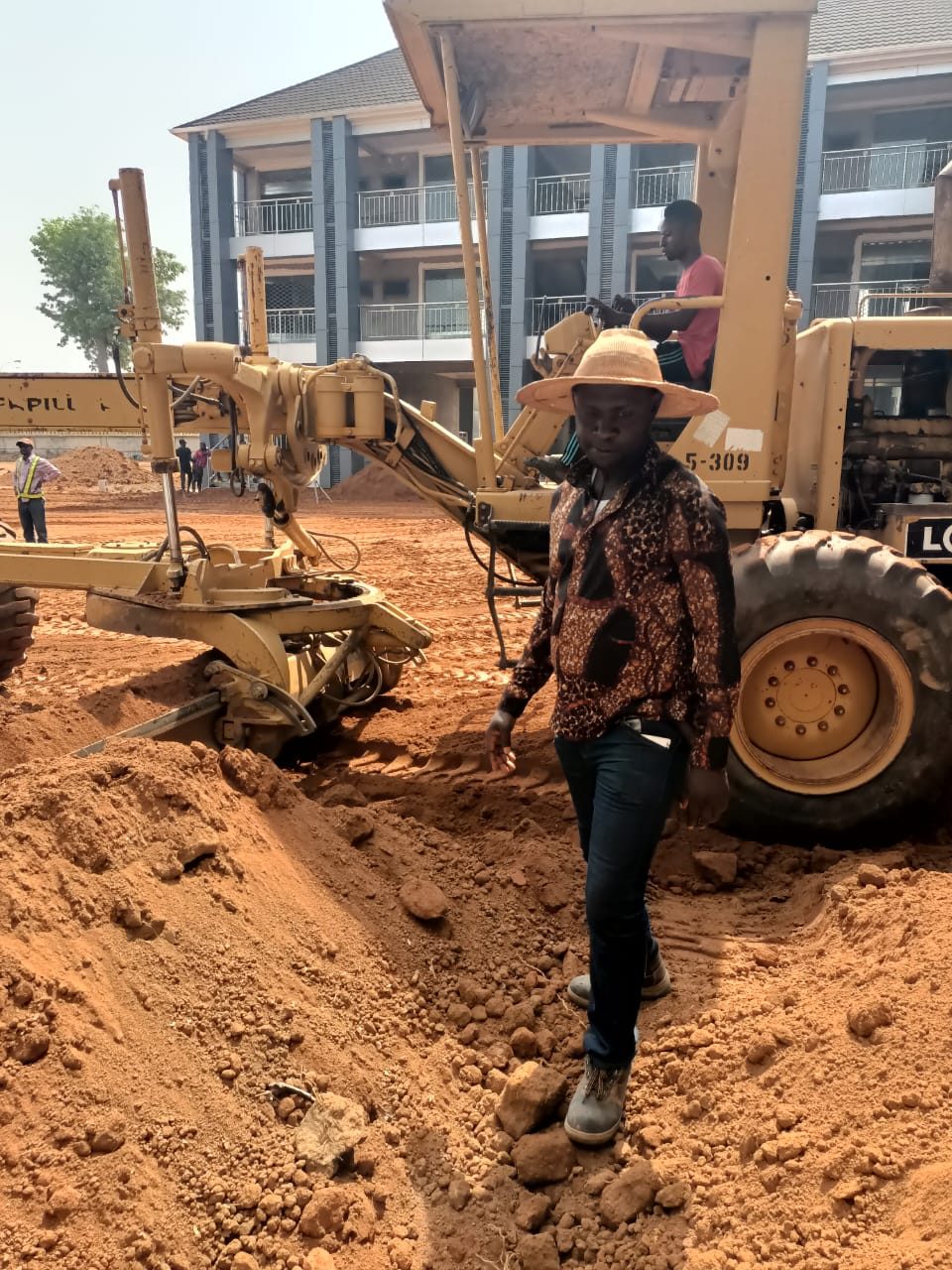 Site engineer beside a motor grader at an institutional building development